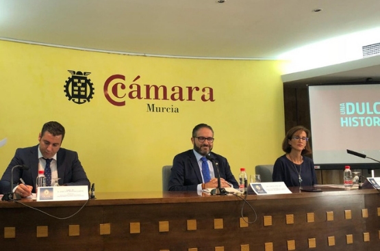 Tres personas sentadas con un cartel de la Cámara de Comercio de Murcia como fondo