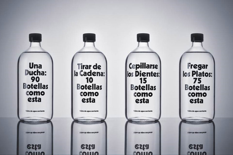 Cuatro botellas de cristal con mensajes de concienciación sobre el agua que contienen